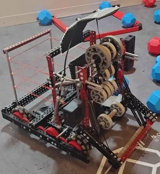 Photo of the first iteration built on the field tiles, with elastic bands and gears visible.